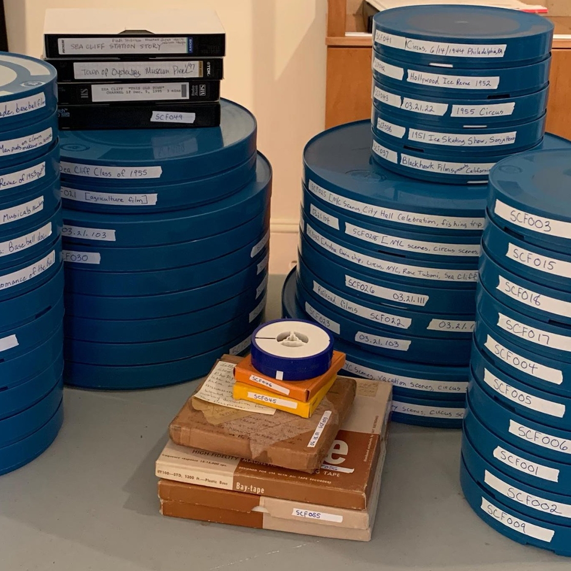 image of multiple large stacks of 35 mm film prints in blue film cannisters, with cardboard boxes in the middle. 