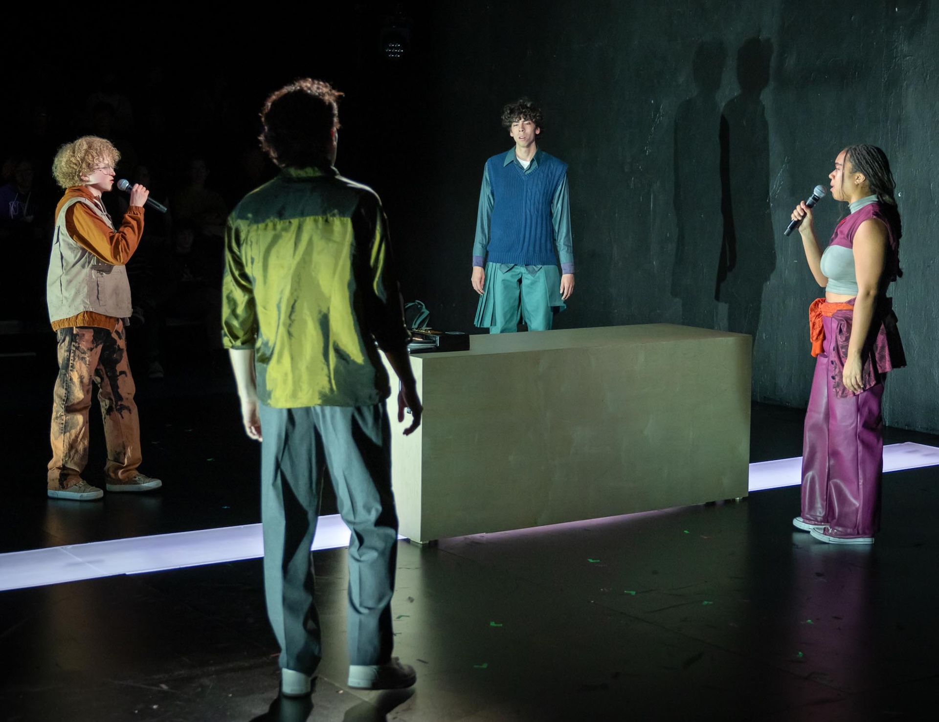 four actors standing in a circle singing