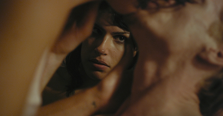 Film Still from Appropriate Behavior, a woman watching a couple kiss.