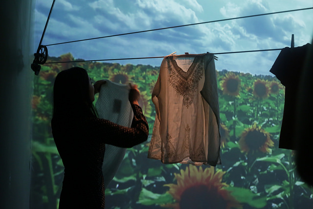 Camper hangs clothes on clothesline in front of projection of Sunflower patch