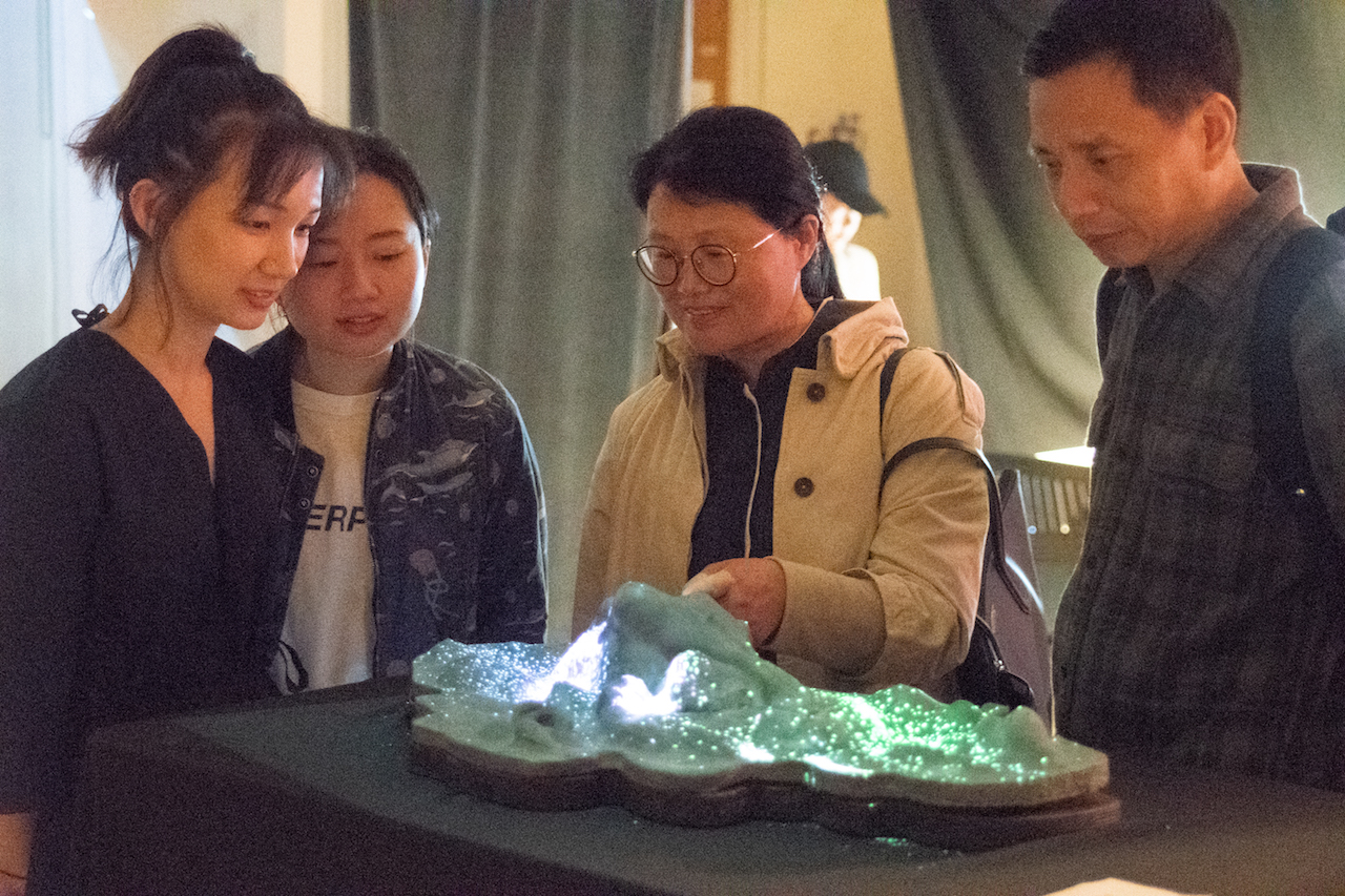 ITP student and guests look at light-up landscape model