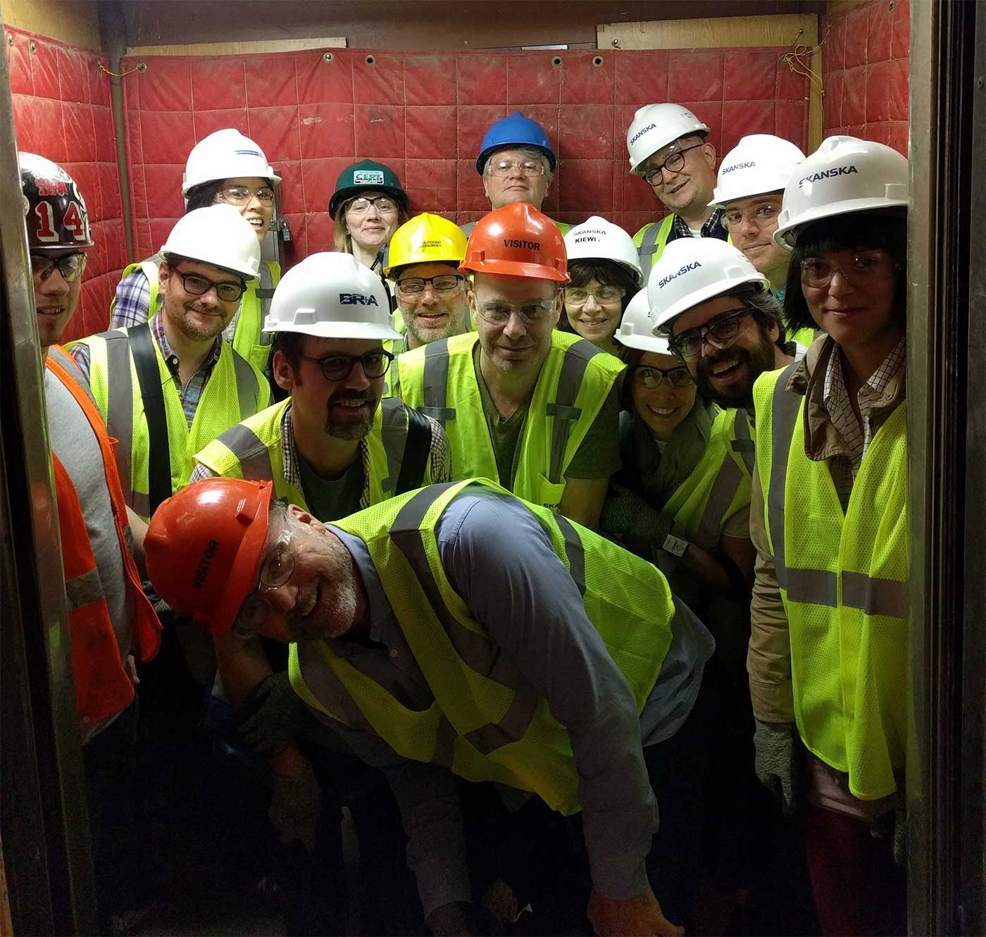a grtoup of people smiling and wearing hard hats