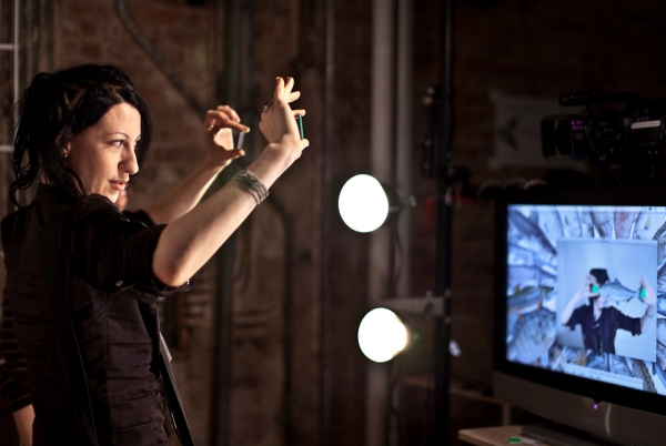 A woman holding up 2 objects as a sensor detects the location of the objects on a screen.