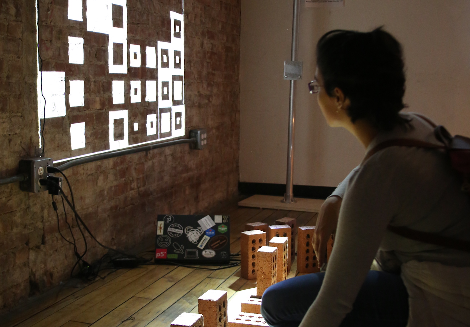 a person interacting with bricks while looking at black and white squares projected on the wall