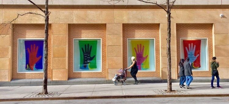Window displays at NYU Kimmel building of banners showing hands