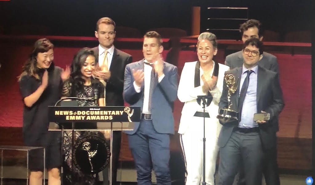 A team of people including Yasmin and Elie standing onstage accepting their award at the News and Documentary Emmys