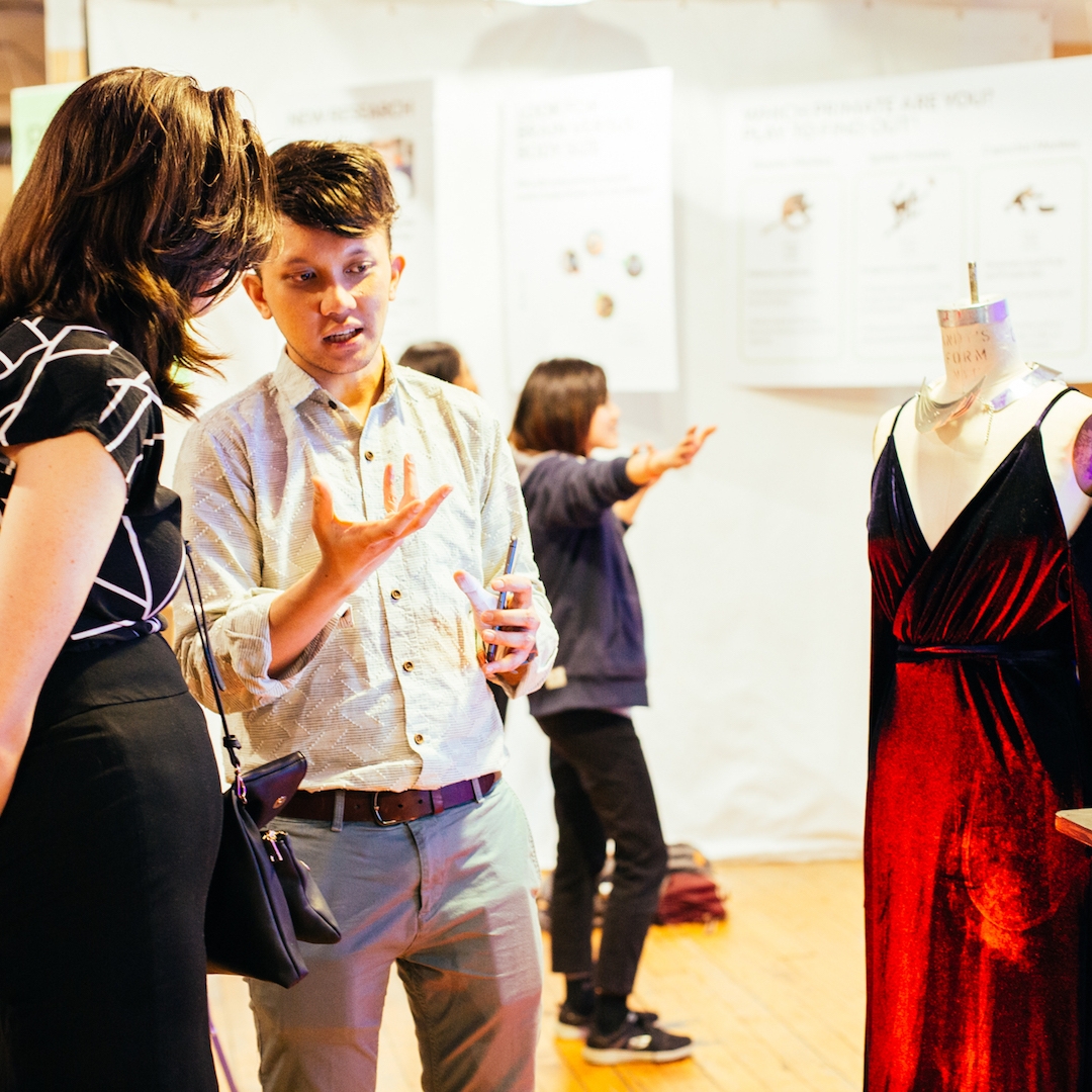 Student explains project of dress on mannequin to guest