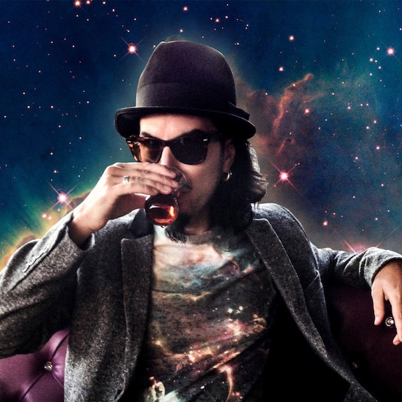 Image of Memo Akten, sipping a drink on a leather couch in outer space