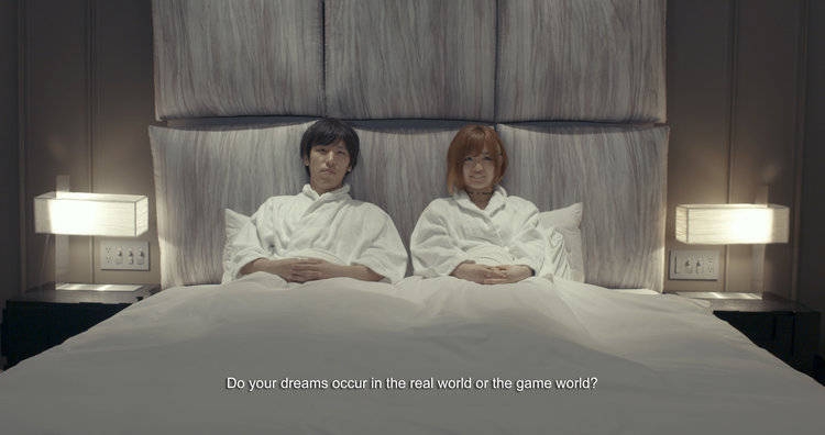 Man and woman sitting up in bed of a modern-looking room, with the question "do your dreams occur in the real world or the game world?"
