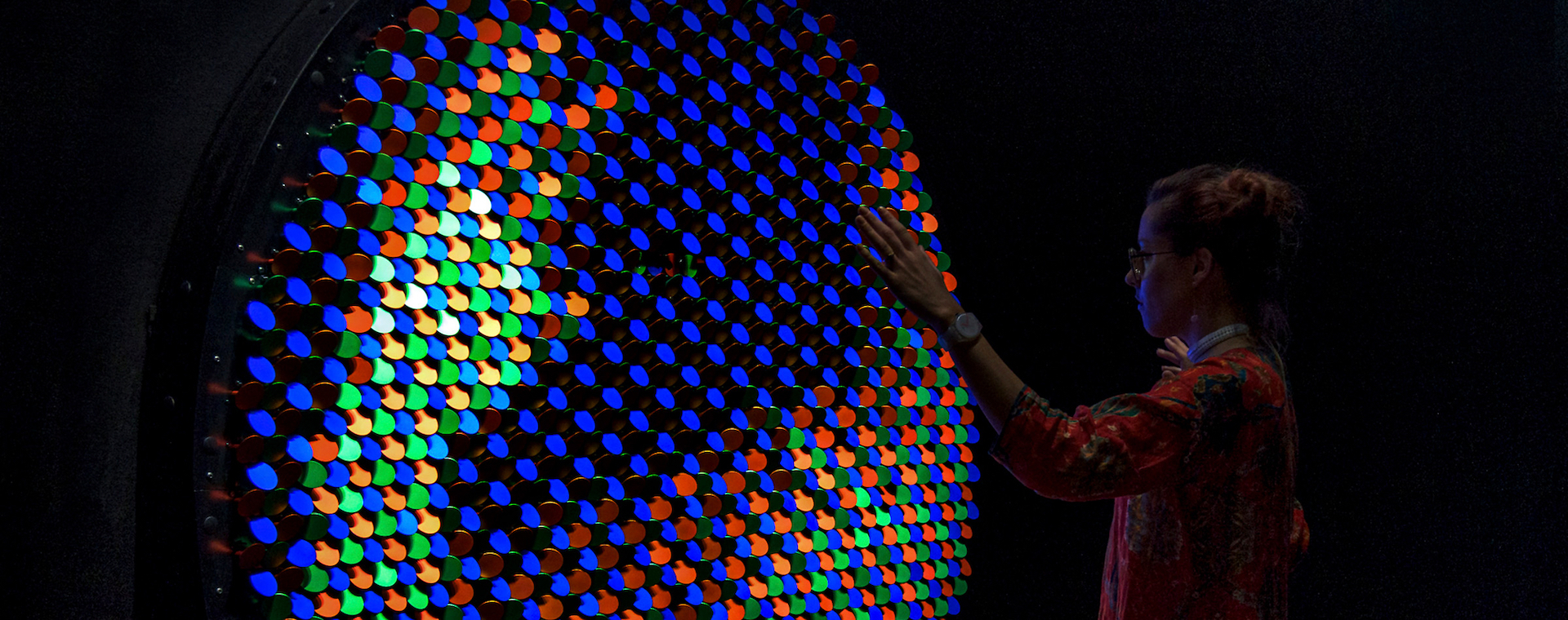 Woman looking into a multi-colored panel of lights