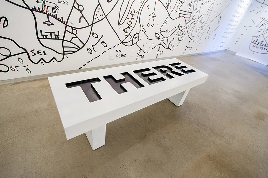 a bench that shows the word There with black drawings on the wall