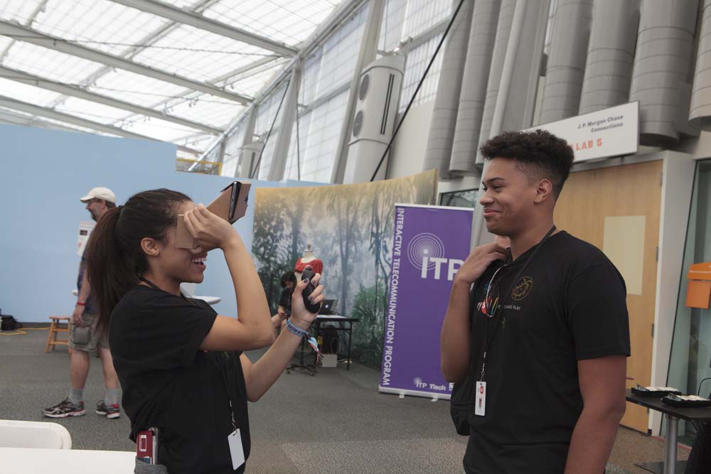 A woman using Google Cardboard while a man looks on smiling