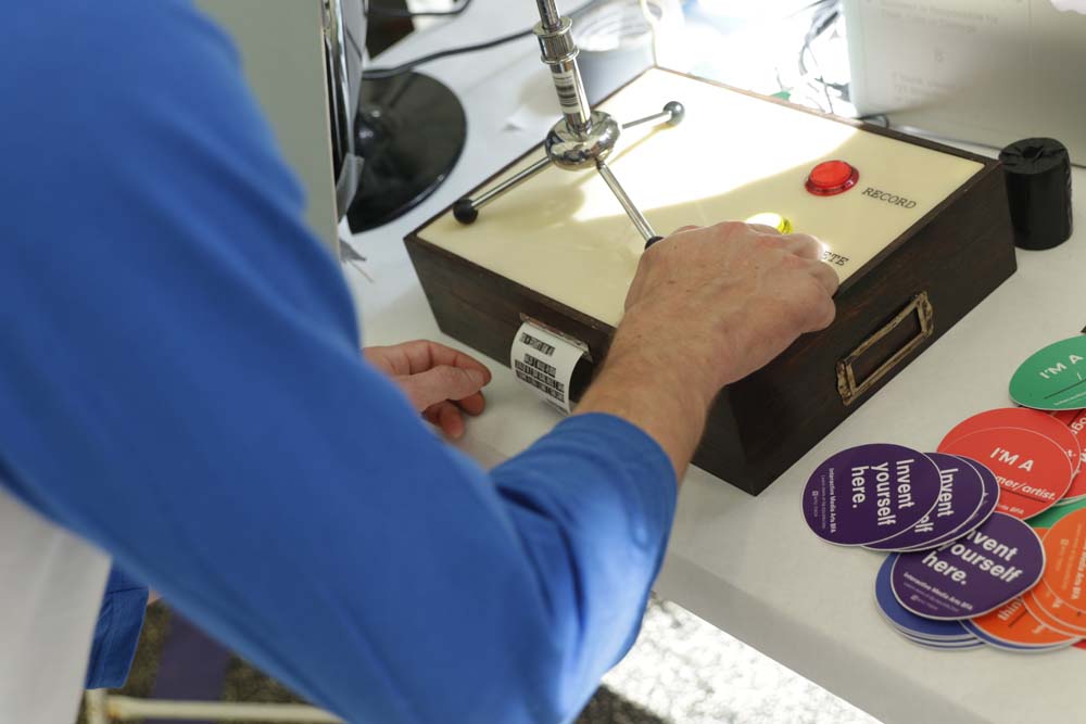 A hand pressing buttons on a box with a receipt being printed