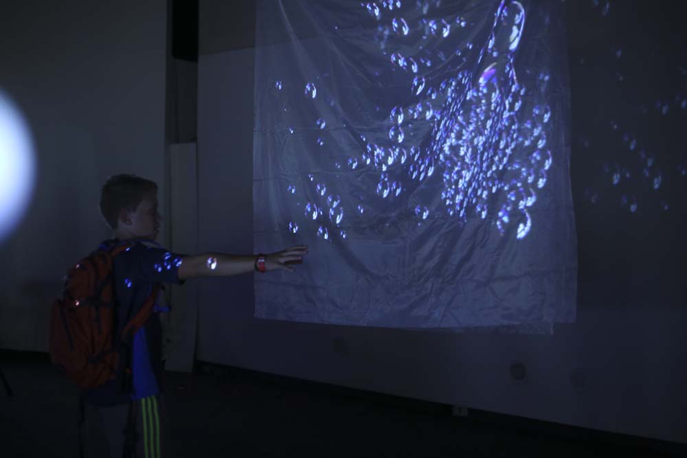 a boy interacting with a projection of bubbles
