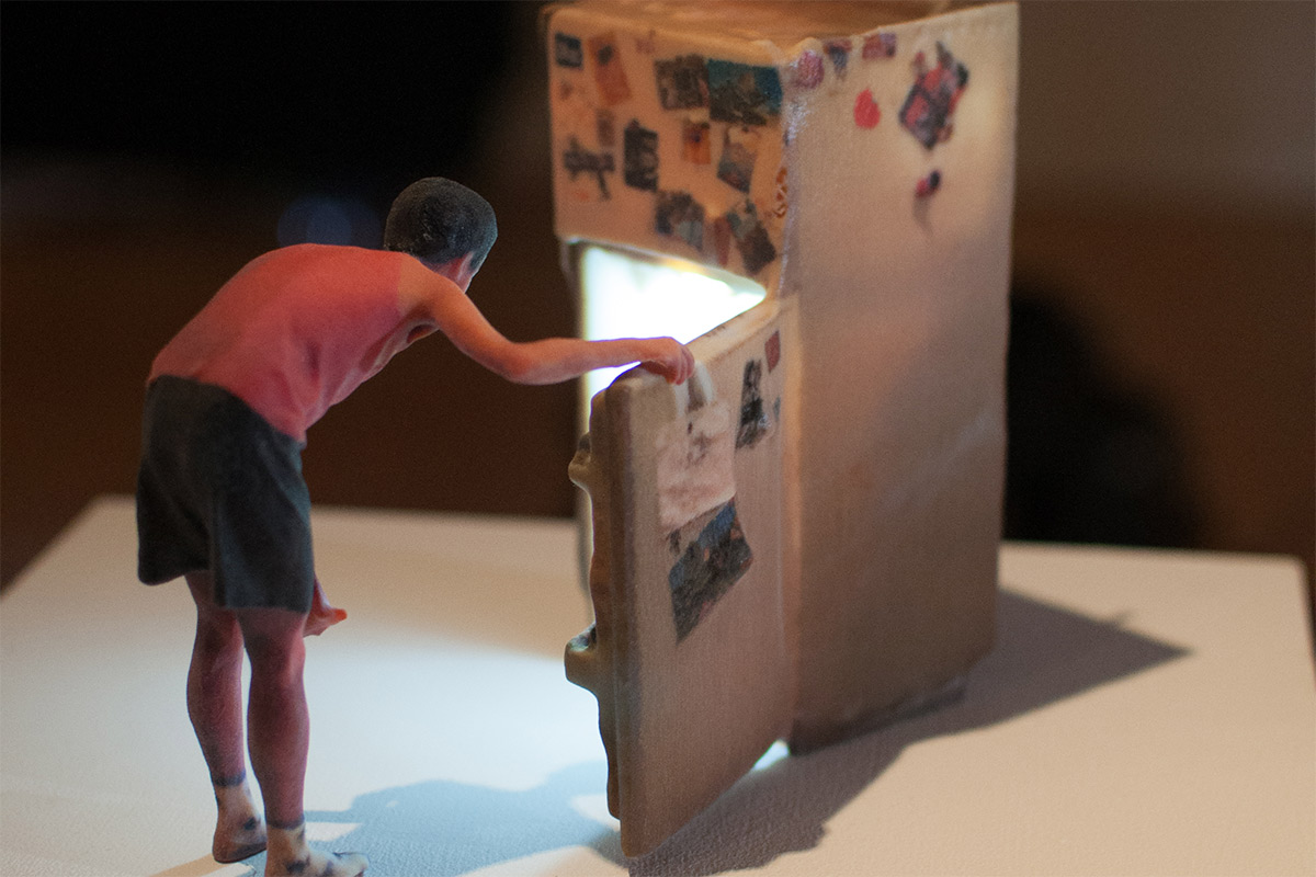 a miniature sculpture of a person looking inside a refrigerator