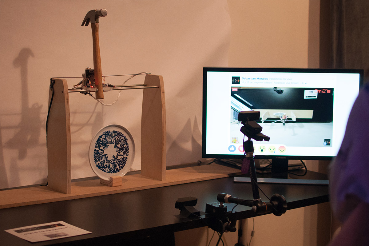 A hammer propped up, ready to swing down and break a plate, next to a monitor