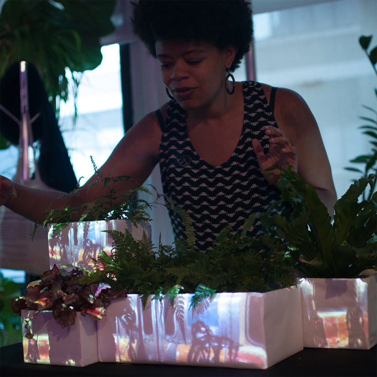a woman with potted plants with projections on the pots