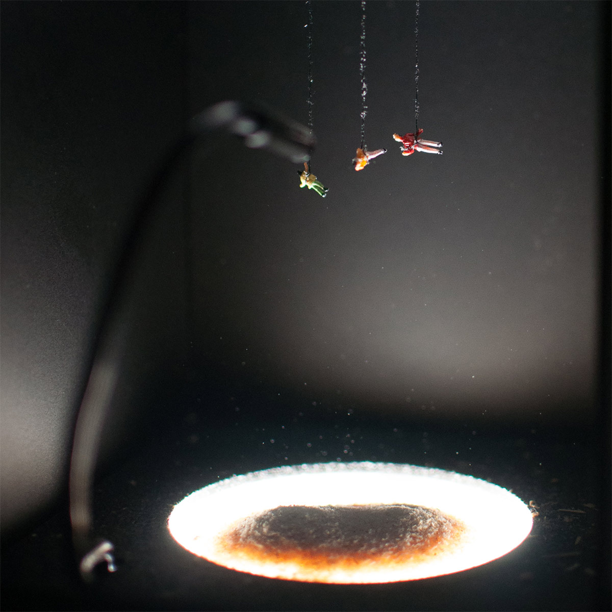 miniature people suspended in air above a pit