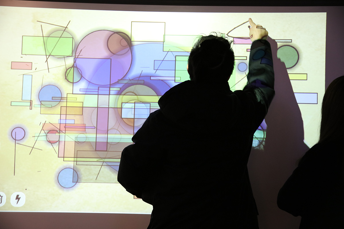 a projection of shapes of different colors and a person drawing his own shape