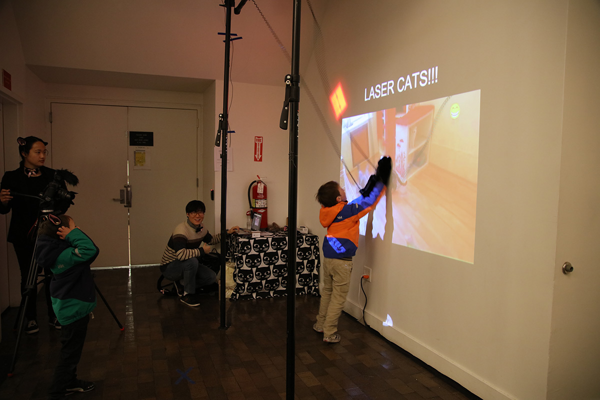 a boy wearing a glove interacting with a cat projected on the wall