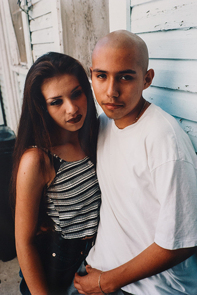 A young Chicano couple pose in embrace