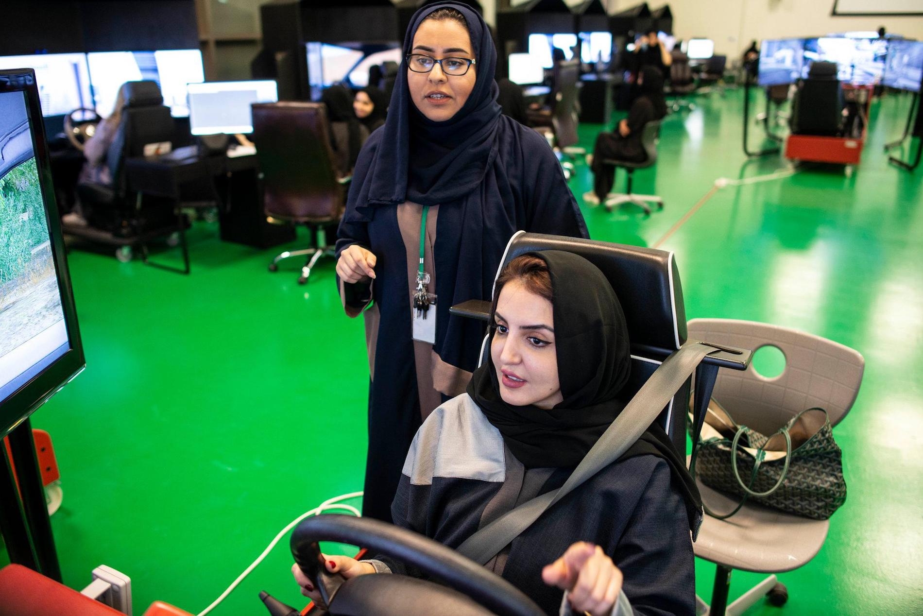 A woman teaches another woman how to drive on a virtual machine.