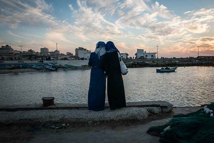 Photo of girls watching the sun set at the harbor in Gaza City