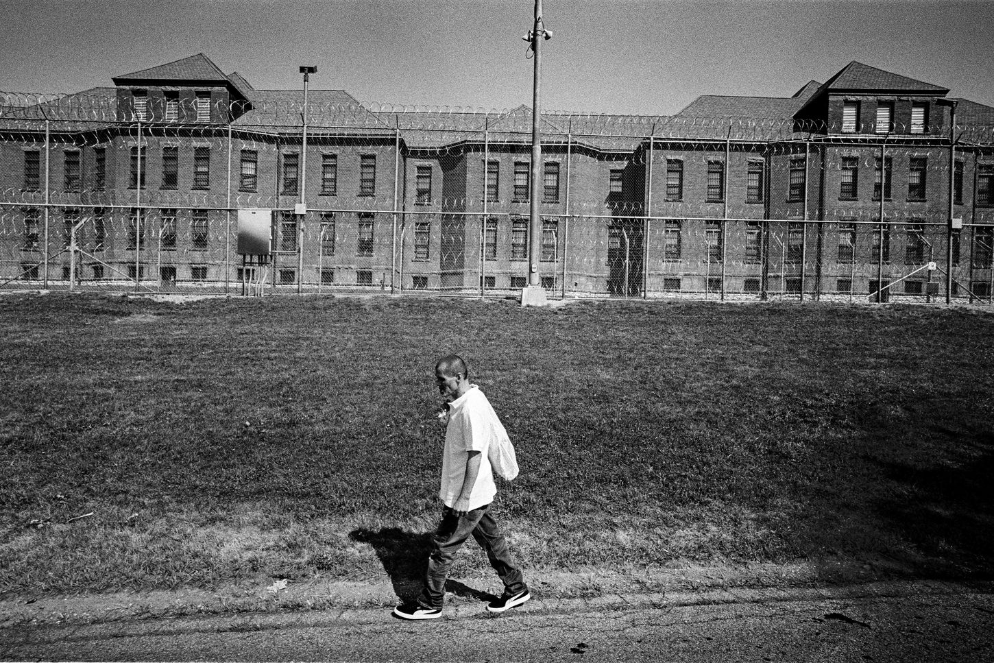 black & white photo of a prisoner walking away from his former place of incarceration, Fishkill Correctional Facility in New York