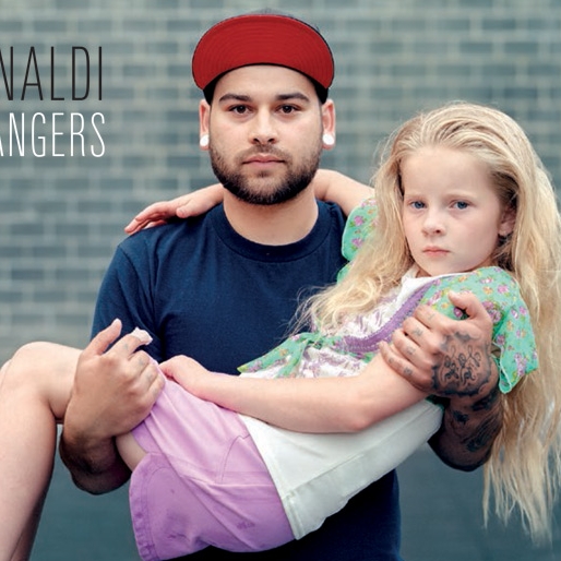 A photo by Richard Renaldi depicting two strangers; An adult male holding a young girl in his arms. 