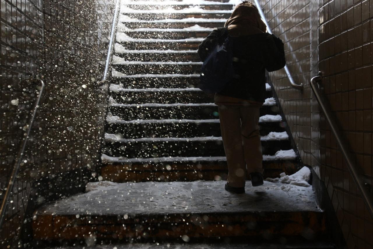 person walks up snowy subway steps