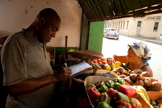 Man selling fruit and vegetables at a produce stand.