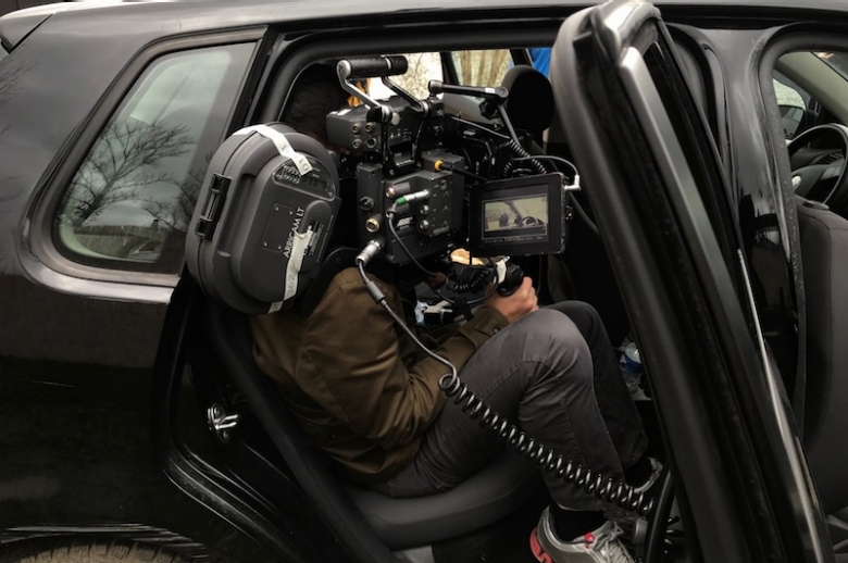 35mm camera and filmmaker seated in a car. 