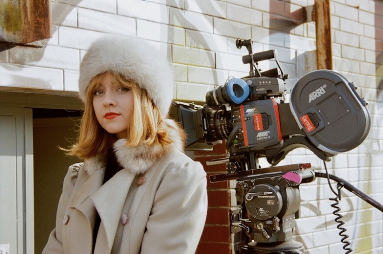 Young actress standing in front of a 35mm camera.