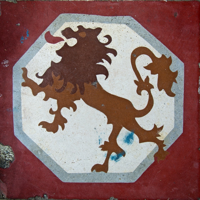 Lion painted on a white background and bordered in red on ceramic tile. 