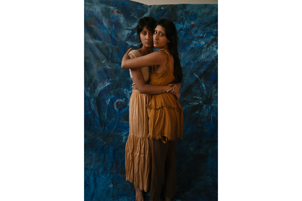 Two people hugging against a blue backdrop