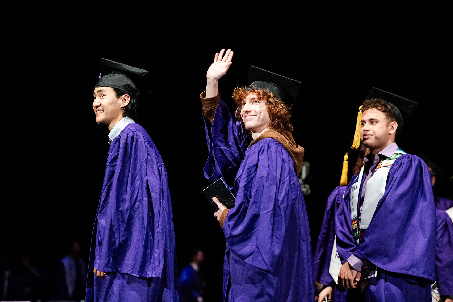 Tisch graduate on stage with one waving