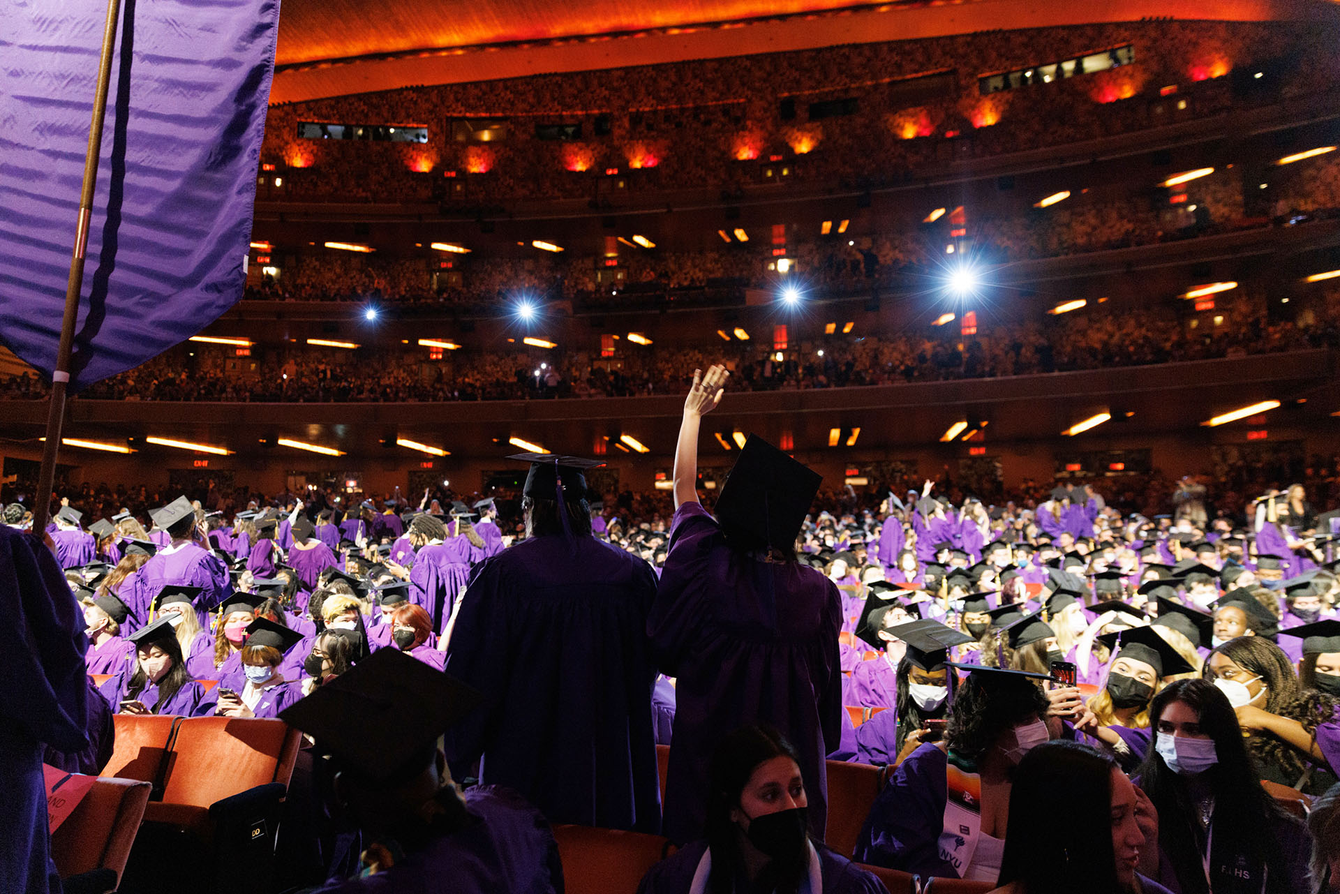 Graduates cheer and waving at Tisch Salute Ceremony at Radio City Music Hall