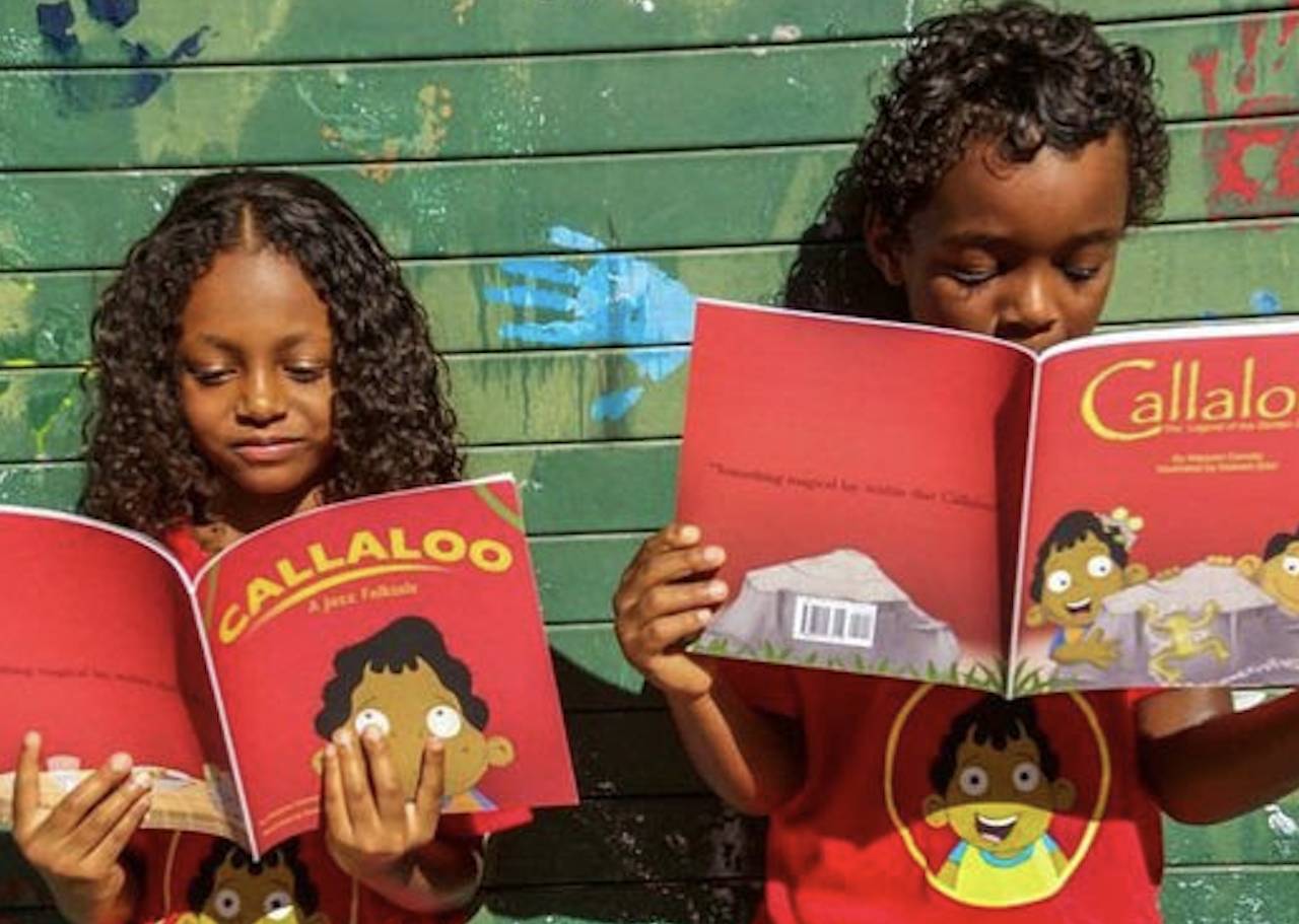 Two children standing against a wall reading books from the series, "Callaloo Kids."