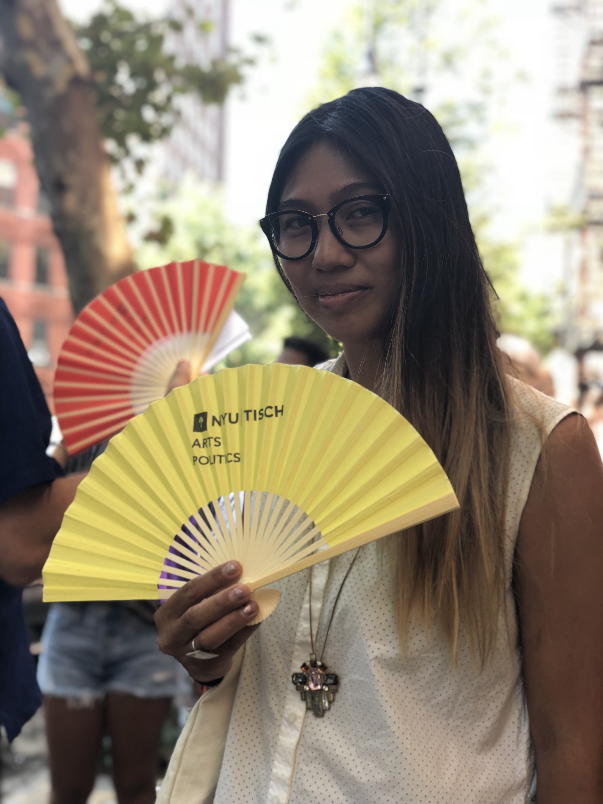 Kristel Baldoz holds a yellow Art & Public Policy Fan 