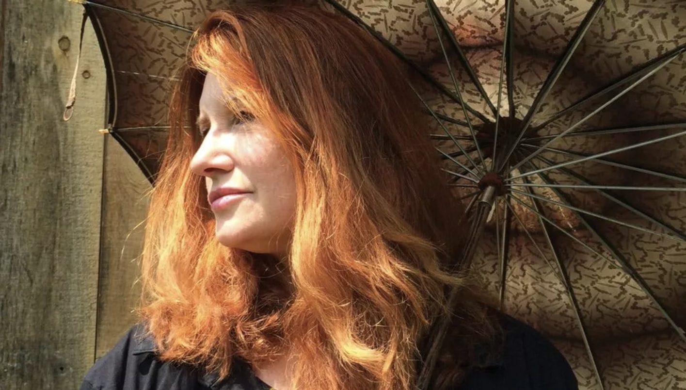 A side profile of Professor Karen Finley under an umbrella.