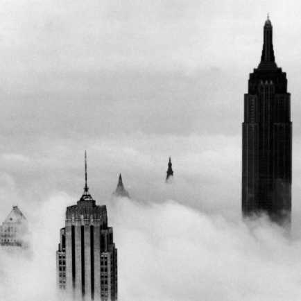 The tops of skyscrapers with fog.