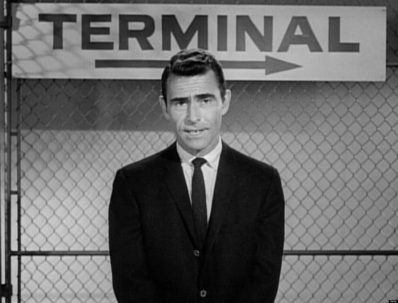 Rod Serling, creator of the television series The Twilight Zone, standing in front of a sign that says 'Terminal'.