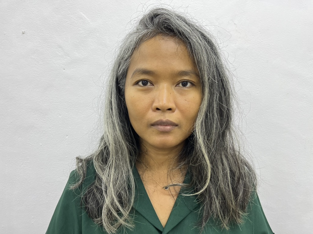 Woman with long grey hair and a green shirt