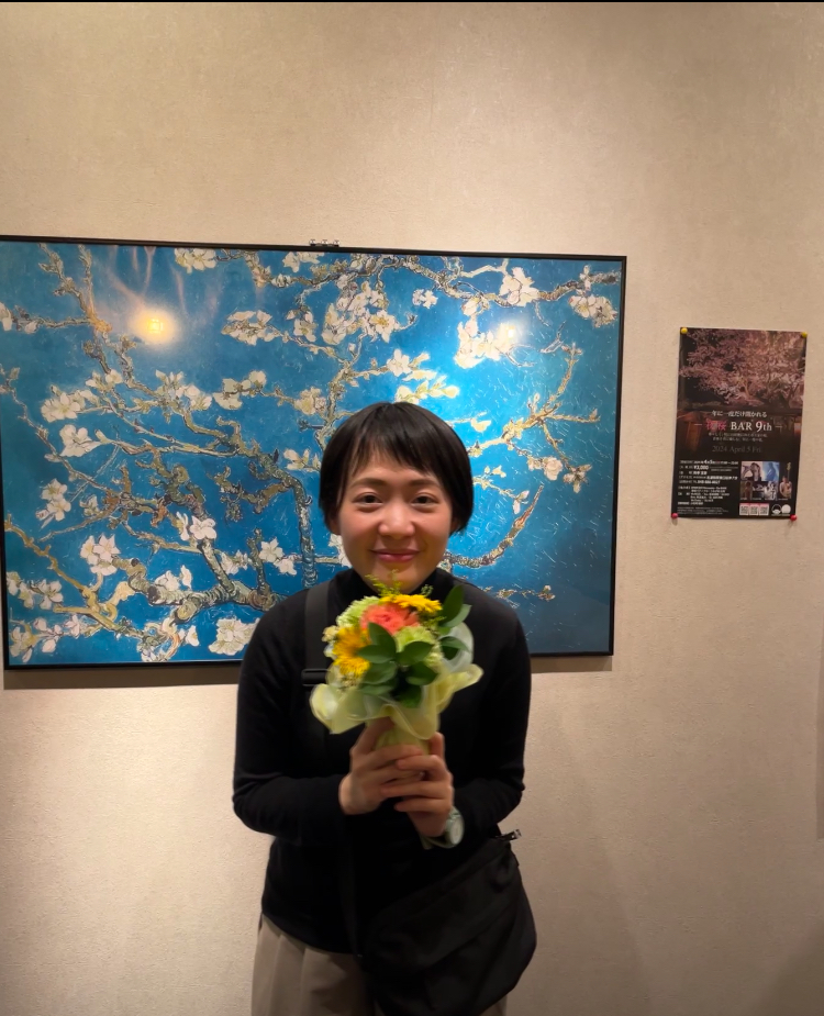 Woman with short hair wearing a dark shirt and holding a bouquet of flowers.