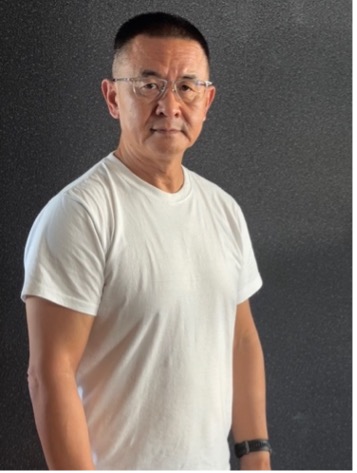 Man with short hair and eyeglasses wearing a white t-shirt.