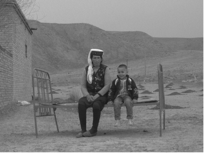 Two people sitting on a wooden fence.