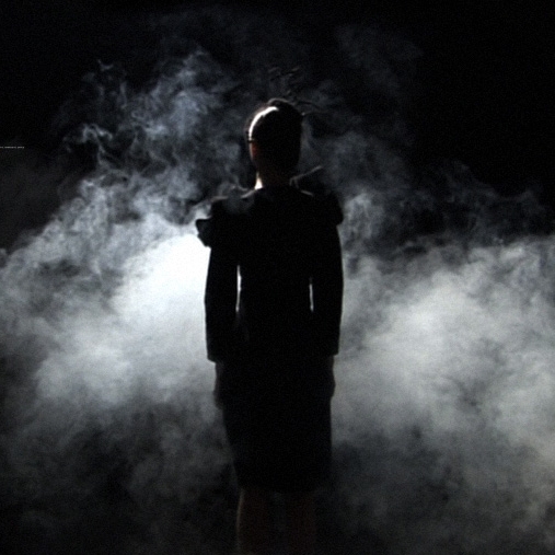 A figure silhouetted with wisps of smoke in the background