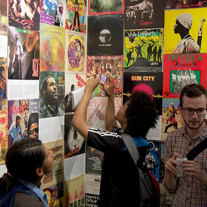 Visitors to the Interference Archive look at their collecion of posters on the wall