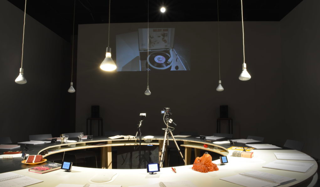 Round table in the center of the room with cameras and papers on top