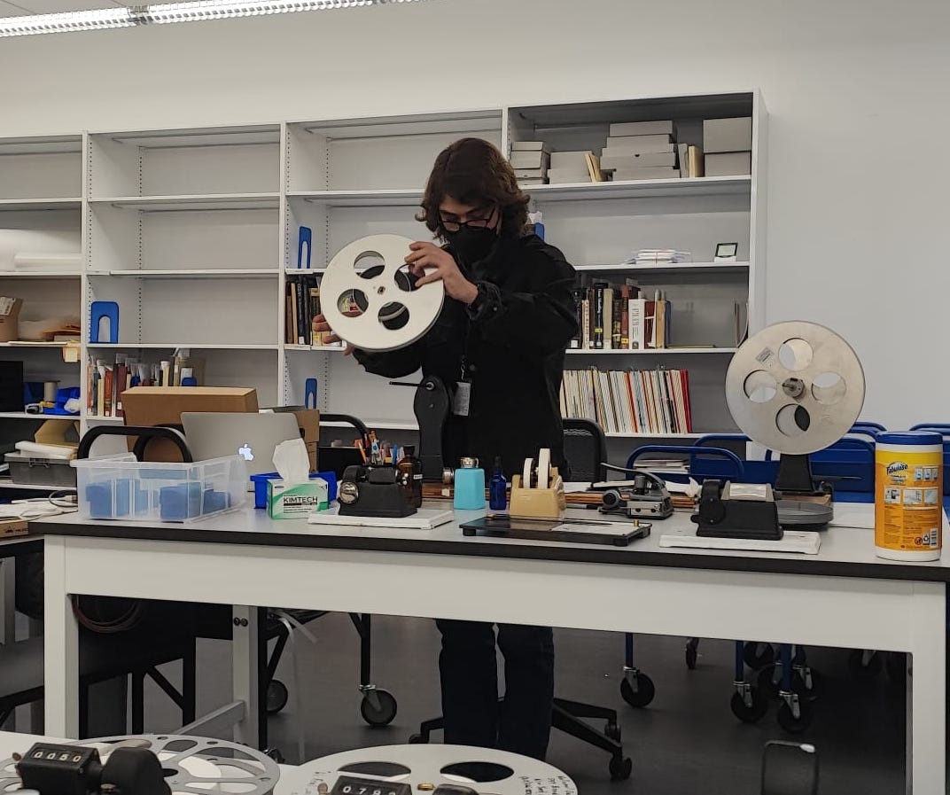 person inspecting a reel of film in a lab
